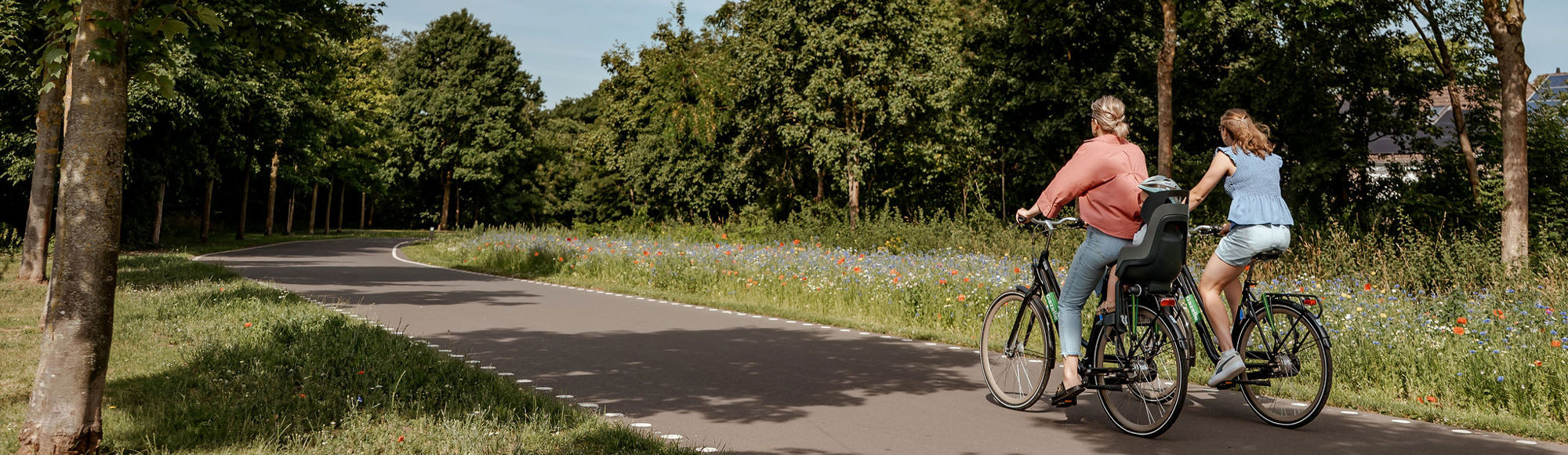 Twee dames fietsen naast elkaar tussen het groen over de Parkstadroute. 