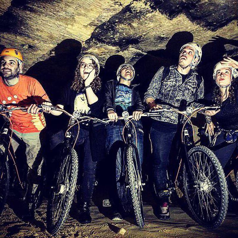 Vijf mensen poseren met mountainbikes in een grot