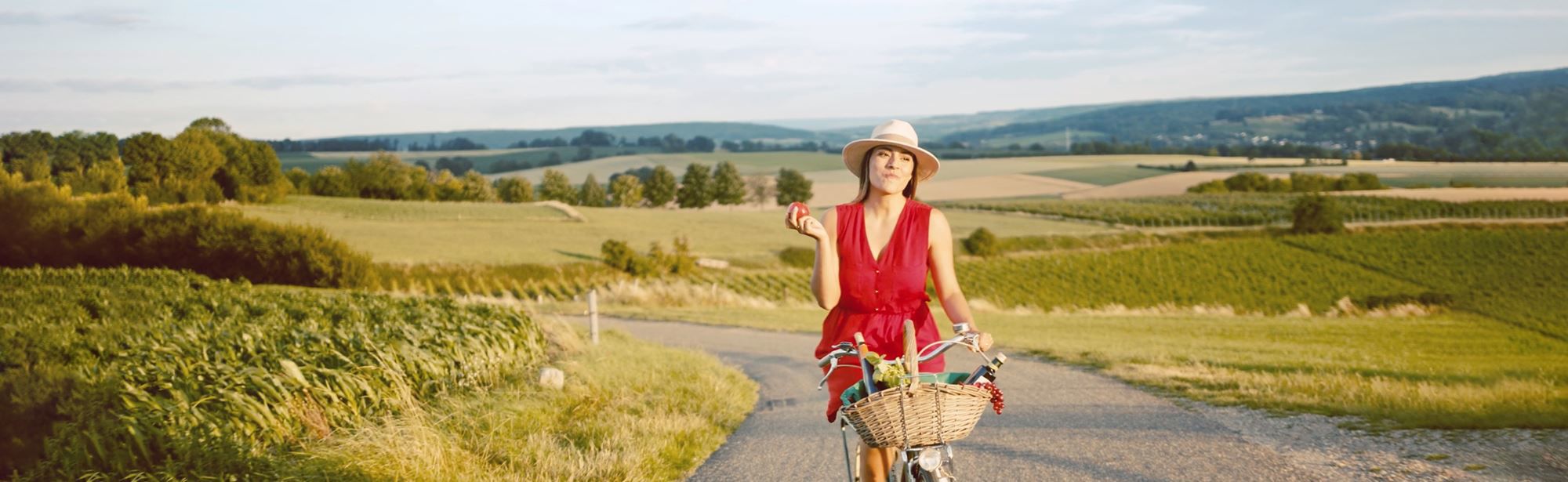 Vrouw in rode jurk fiets op een weg door het Heuvellandschap